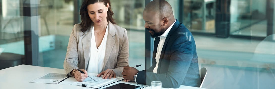 Business professionals sitting at a conference table reviewing documents.